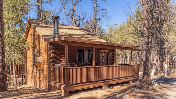 A rustic log cabin with a wooden deck, surrounded by trees. - Forest Cabin 6 Enchanted Forest (Payson)