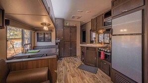 A compact RV kitchen with wooden cabinets, a stove, and a refrigerator.