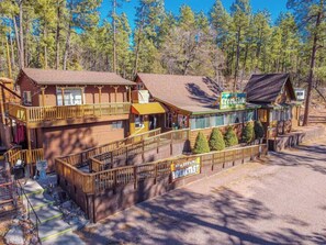 A two-story wooden building with a balcony, a sign for 'Creekside', and a 'Now Serving Breakfast' sign. - Forest Cabin 1 Hunters Blind (Payson)