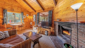 Un intérieur de chalet chaleureux avec une cheminée, des murs en bois, un téléviseur et un coin repas.