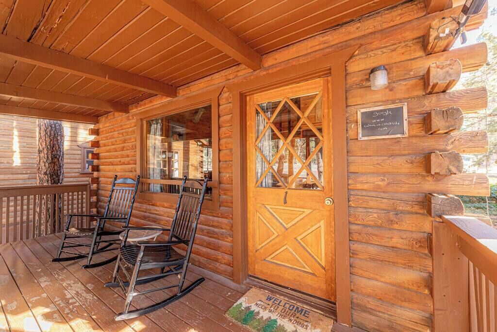 Una cabana de fusta amb un porxo, cadiretes d'oscil·lació i una porta amb felpujada de benvinguda.