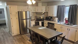 A compact kitchen with white cabinets, a stainless steel refrigerator, a microwave, a stove, and a sink. - Forest Cabin 7 Seventh Heaven (Payson)