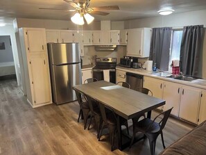 A compact kitchen with white cabinets, a stainless steel refrigerator, a microwave, a stove, and a sink. - Forest Cabin 7 Seventh Heaven (Payson)