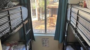 A dormitory room with bunk beds, a window with curtains, and a view of the outdoors. - Forest Cabin 7 Seventh Heaven (Payson)