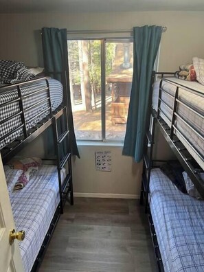A dormitory room with bunk beds, a window with curtains, and a view of the outdoors. - Forest Cabin 7 Seventh Heaven (Payson)