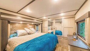 Un dormitorio con una cama grande, un aparador, un espejo y una ventana.