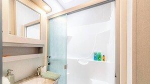 Un baño con lavamanos, espejo y ducha.
