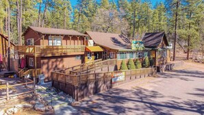A lodge with multiple wooden buildings, a covered walkway, and a sign indicating 'Mon Serv. 5:00 AM - 9:00 PM'. - Forest Cabin 3 Bear's Den (Payson)