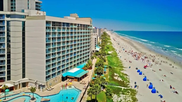 A hotel with a pool, beach, and ocean view.