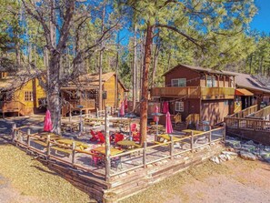 A rustic cabin with a deck, outdoor seating, and a large tree in the foreground. - Quaint condo retreat 12 Ridgeview Condo (Payson)