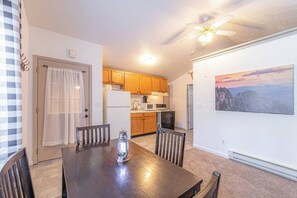 A dining area with a wooden table and chairs, a ceiling fan, and a kitchen in the background. - Quaint condo retreat 12 Ridgeview Condo (Payson)