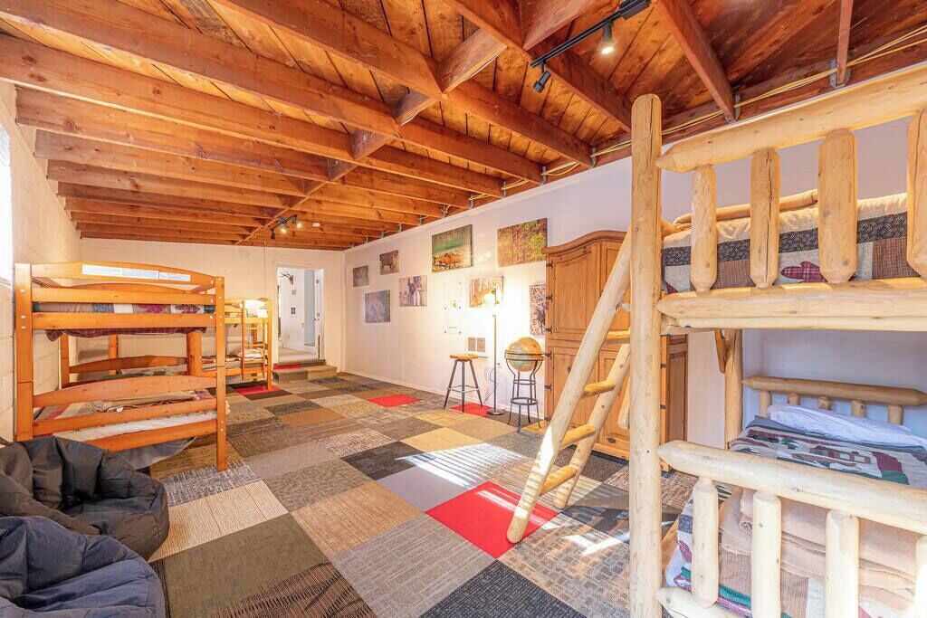 Um quarto aconchegante com beliches de madeira, uma escada e um piso quadriculado e colorido.