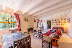 A cozy living room with a fireplace, a checkered sofa, a dining table with a jigsaw puzzle, and a bookshelf. - Forest Home Retreat 11 Ridgeview Retreat (Payson)