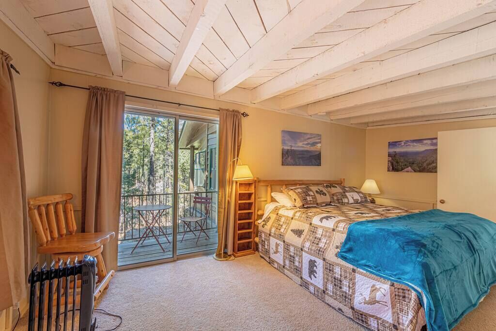 Un dormitorio con una cama grande, una silla, una mesa y vistas al exterior.