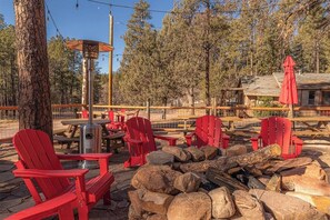 An outdoor seating area with red chairs, a fire pit, and a wooden deck. - Forest Home Retreat 11 Ridgeview Retreat (Payson)