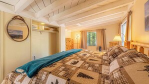 Ett sovrum med en säng, en spegel, en garderob och ett fönster med gardiner.
