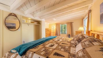 A bedroom with a bed, a mirror, a wardrobe, and a window with curtains.