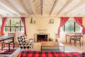 Una habitación acogedora con chimenea, muebles de madera y ventanas grandes con cortinas.