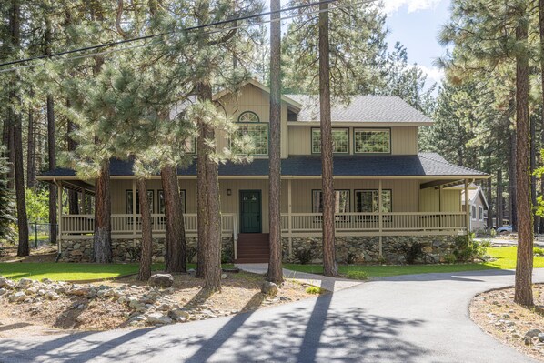 A two-story house with a stone foundation, a front porch, and a driveway leading to the entrance. - Fun Family Cabin in the Heart of the Lost Sierra w/ BBQ, Games and Tons of Space (Graeagle)