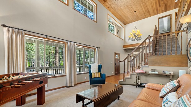 A spacious living room with a foosball table, a sofa, a coffee table, and a staircase leading to an upper level.