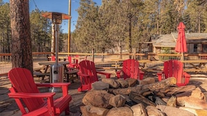 An outdoor seating area with red chairs, a fire pit, and a wooden deck. - Forest Cabin 4 Cowboys Dream (Payson)