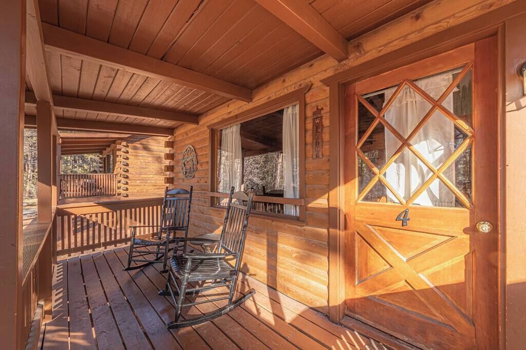 Une cabane en bois avec une véranda, des fauteuils à bascule et une porte portant le numéro 4.