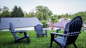 A grassy outdoor area with two Adirondack chairs and a small table, surrounded by houses and trees. - "Rebel Base" in the  Heart of Fayetteville (Fayetteville)