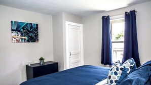 A bedroom with a bed, a nightstand, a door, and a window with curtains. - "Rebel Base" in the  Heart of Fayetteville (Fayetteville)