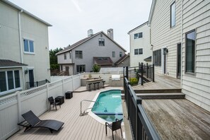 Relax by the pool surrounded by a deck with lounge chairs and a grill.