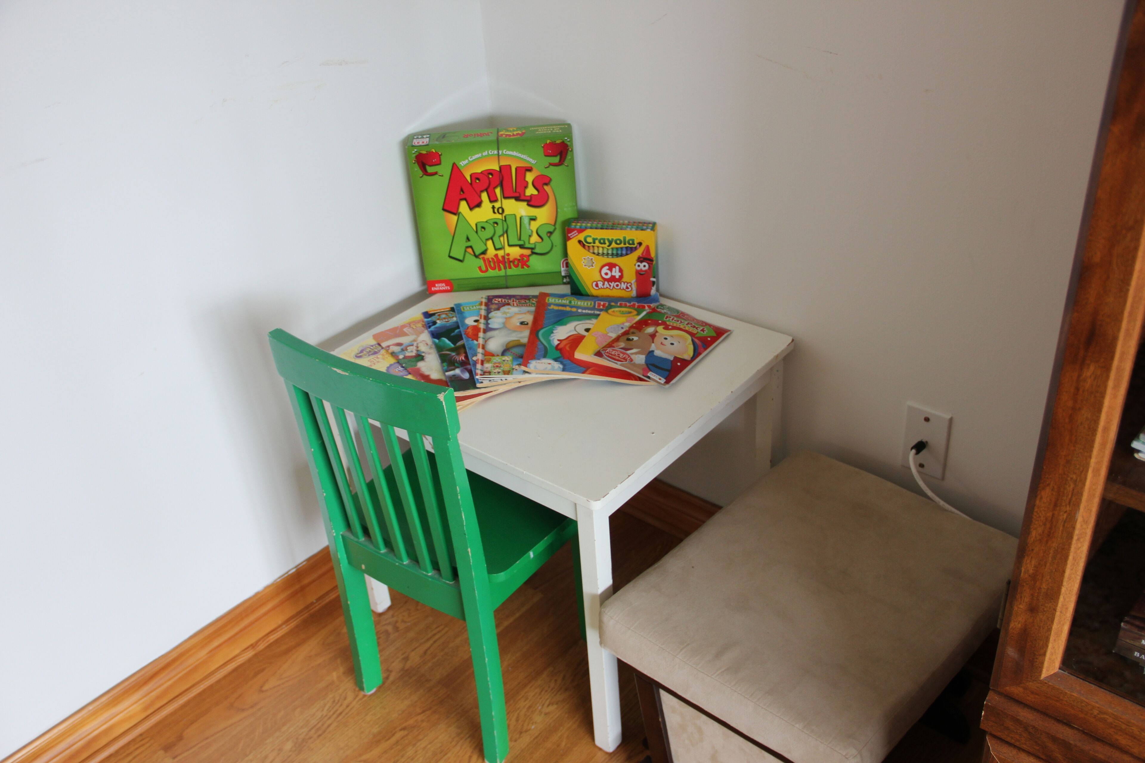 A small table with a green chair, a box of crayons, and several children's books.