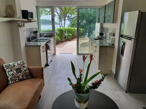 A modern kitchen with a view of the sea, a sofa, and a potted plant. - Unique & lovely beachfront apartment. (Provincia de Guanacaste)