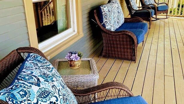 Une véranda couverte, aménagée avec des meubles en osier et des coussins bleus.