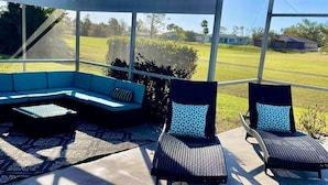 Ein überdachter Außenbereich mit Pool, ausgestattet mit einer Eckcouch und zwei Liegestühlen.