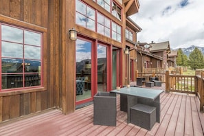 A wooden building with large windows and a deck area with outdoor furniture.
