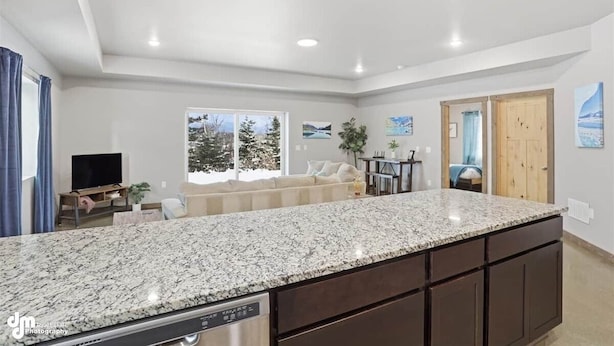A modern kitchen with granite countertops, dark cabinetry, and recessed ceiling lights. - Upper Mesa Villa #9, Glacier Suites - Upper Mesa Villa #11 (Palmer)