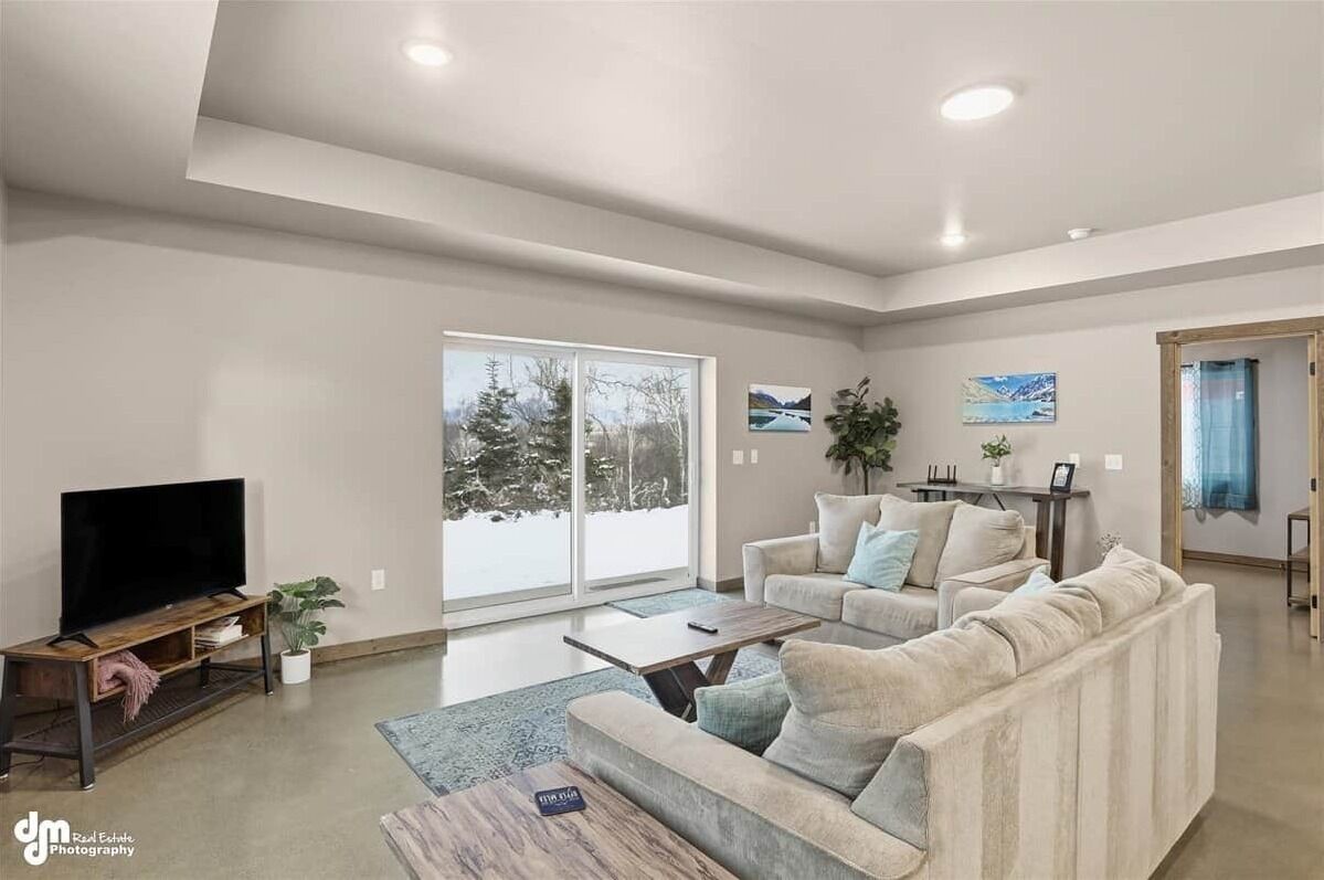 A modern living room with a large window, a flat-screen TV, a sofa, and a coffee table.