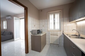 A compact kitchen with a microwave, a radiator, and a sink.