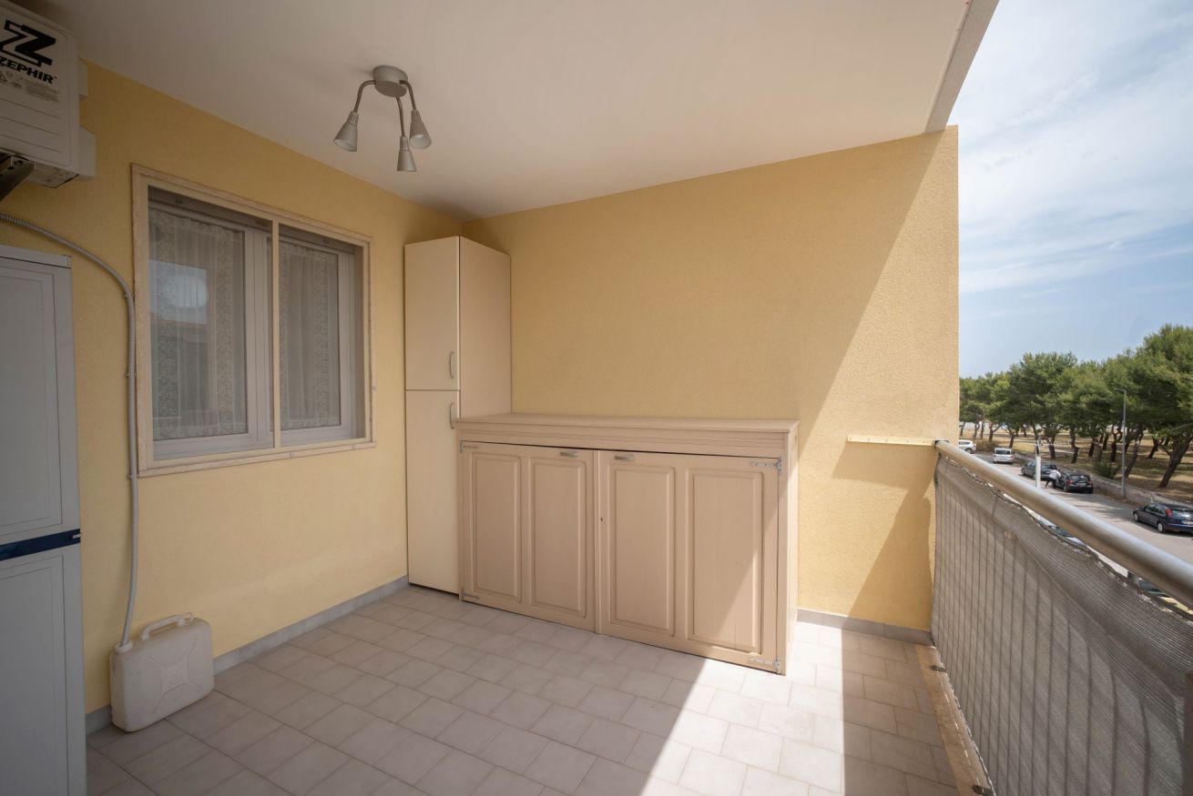 A balcony with a tiled floor, a window with curtains, a cabinet, and a ceiling light fixture.