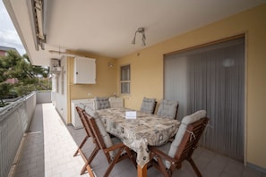 Un espacio cubierto para comer al aire libre, con una mesa, sillas, un armario blanco y una ventana.