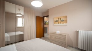 Ein Schlafzimmer mit einem Bett, einem Schminktisch, einem Spiegel, einem Gemälde und einer Heizung.