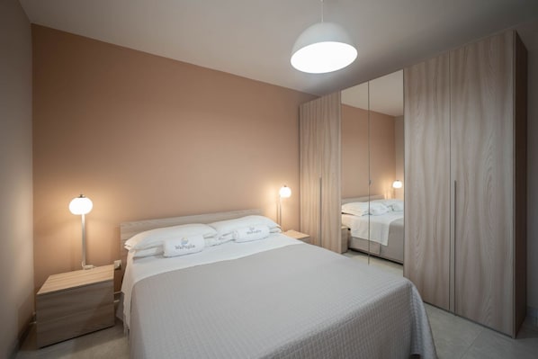 Un dormitorio con cama, lámparas de noche, espejo y armario.