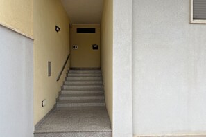 A narrow stairway leading to a landing with a door and a small window. - WePuglia - Appartamento Sibilla (Monopoli)