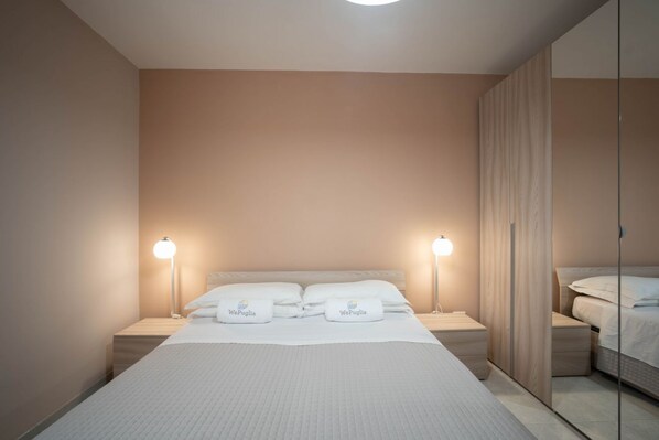 A neatly arranged hotel room with a bed, bedside lamps, a mirror, and a wardrobe.