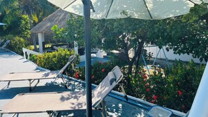 A poolside area with lounge chairs, a thatched-roof structure, and lush greenery. - Welcome to Villa Rosa Bella. Viva la vida Bella (Palmar de Ocoa)