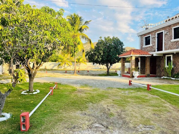 Un edificio con fachada de piedra, tejado de tejas rojas y un pequeño porche con barandilla blanca.