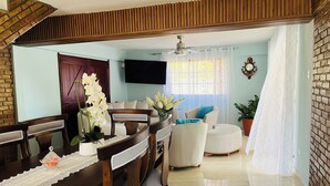A modern living room with a wooden dining table, chairs, a sofa, and a TV. - Welcome to Villa Rosa Bella. Viva la vida Bella (Palmar de Ocoa)