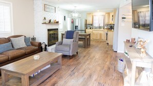 A spacious living room with a fireplace, a dining area, and a kitchen with wooden cabinets. - Remodeled cabin. New Central Air… (Ruidoso)