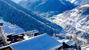 A mountain resort with snow-covered roofs and a view of snow-capped peaks.