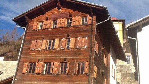 A wooden building with multiple windows and a sloped roof.