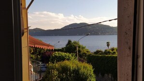 Une vue sur un lac, avec des montagnes en arrière-plan, un bâtiment au toit rouge et un balcon doté d’une balustrade.